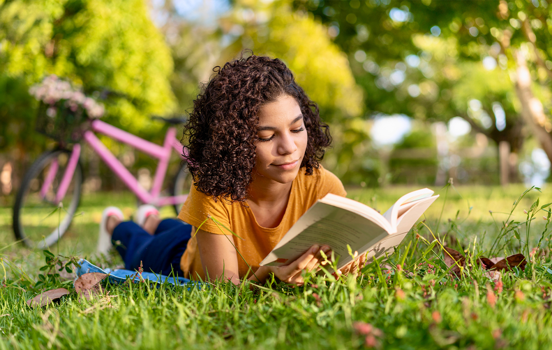 A teenage girl reads a book outside.