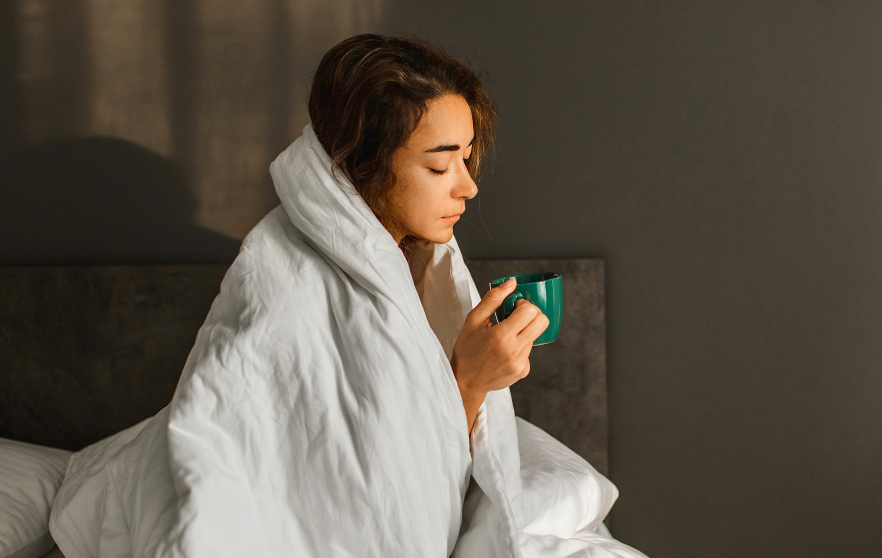 A woman with Tuberculosis sits in bed.