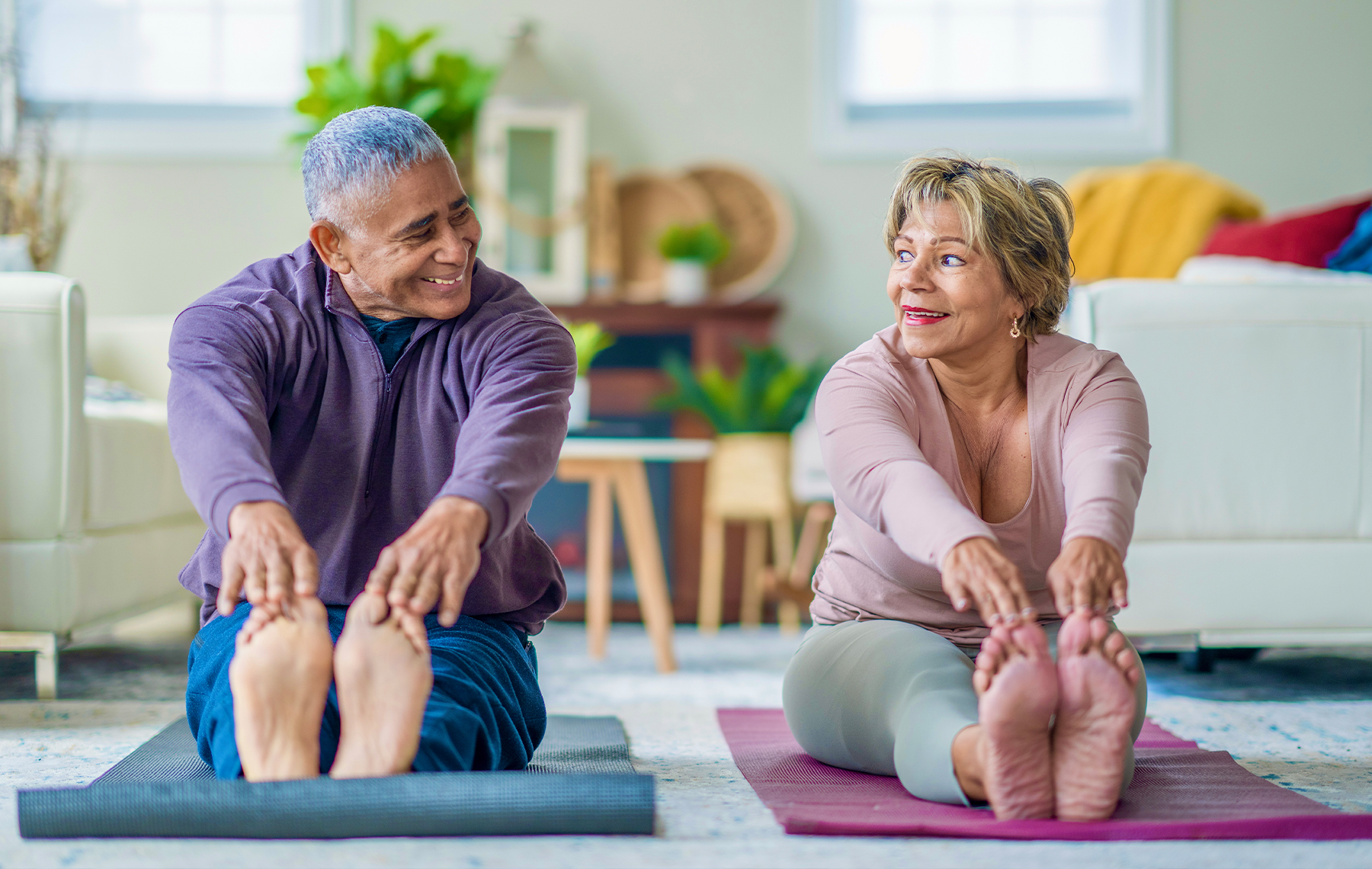 A senior couple does yoga at home.