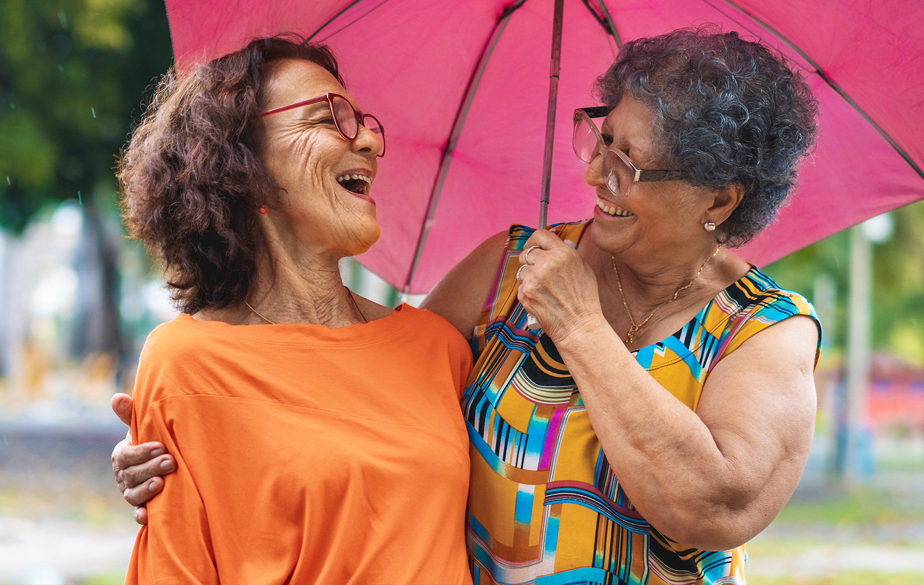Two senior friends connect outside.