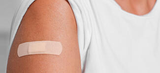 A closeup of a woman's arm with a vaccine bandage.
