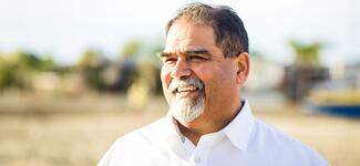 A senior man smiles outdoors.