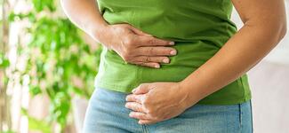 A woman holds her stomach in pain.