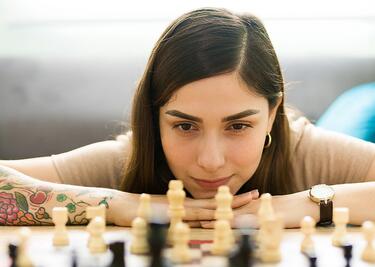 A young woman plays chess in her home.