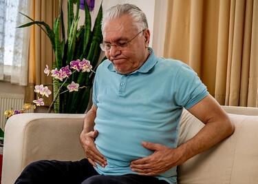 A man experiences stomach pain in living room.