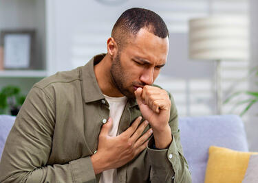 A man with Tuberculosis coughs at home.